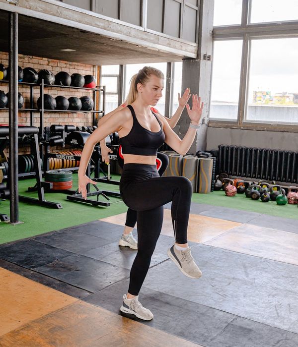Woman performing a light, dynamic cardio exercise in a bright studio.